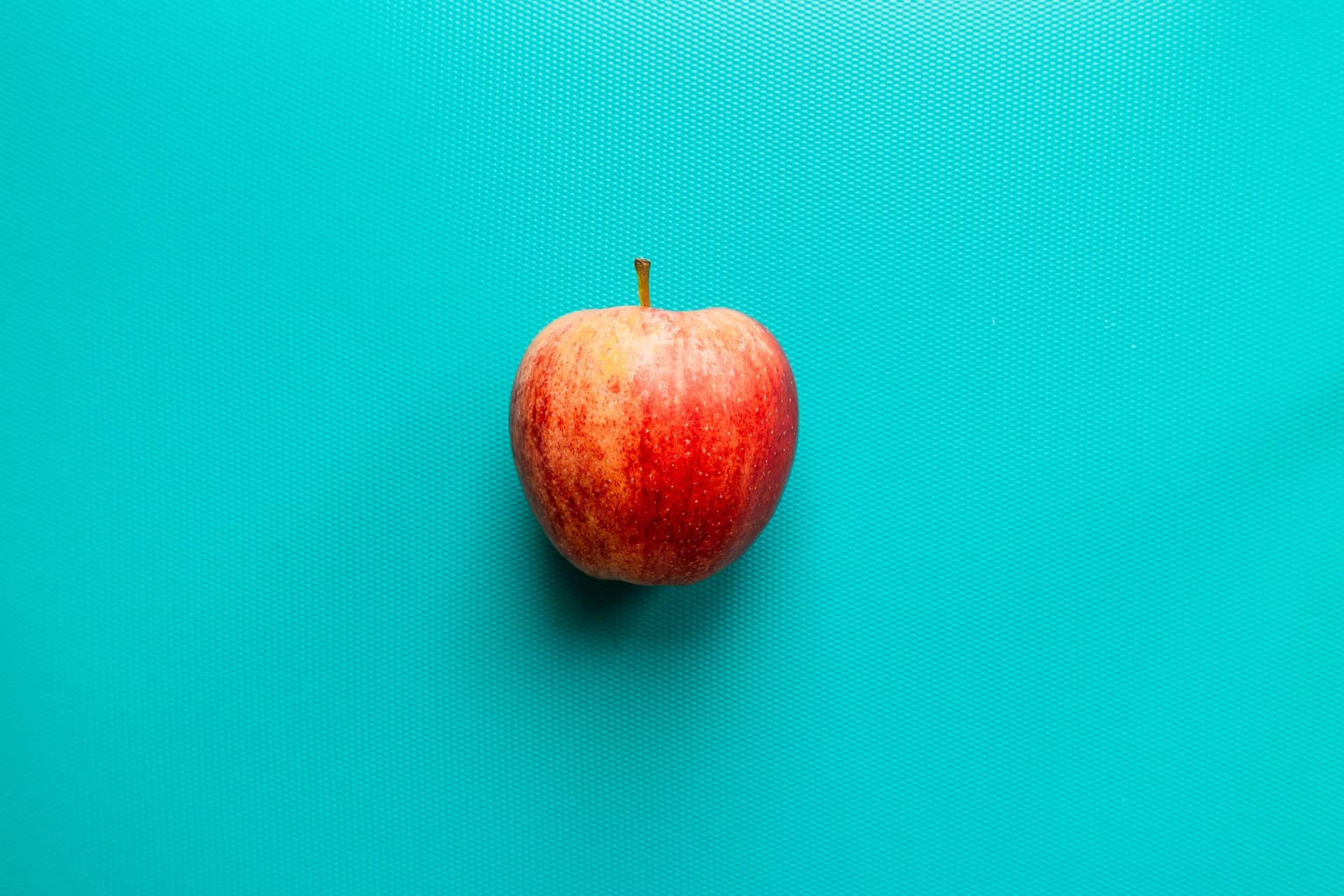 A red apple on a turquoise background.